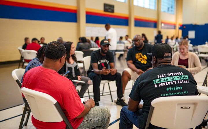 Seven people sit in a circle at a convening