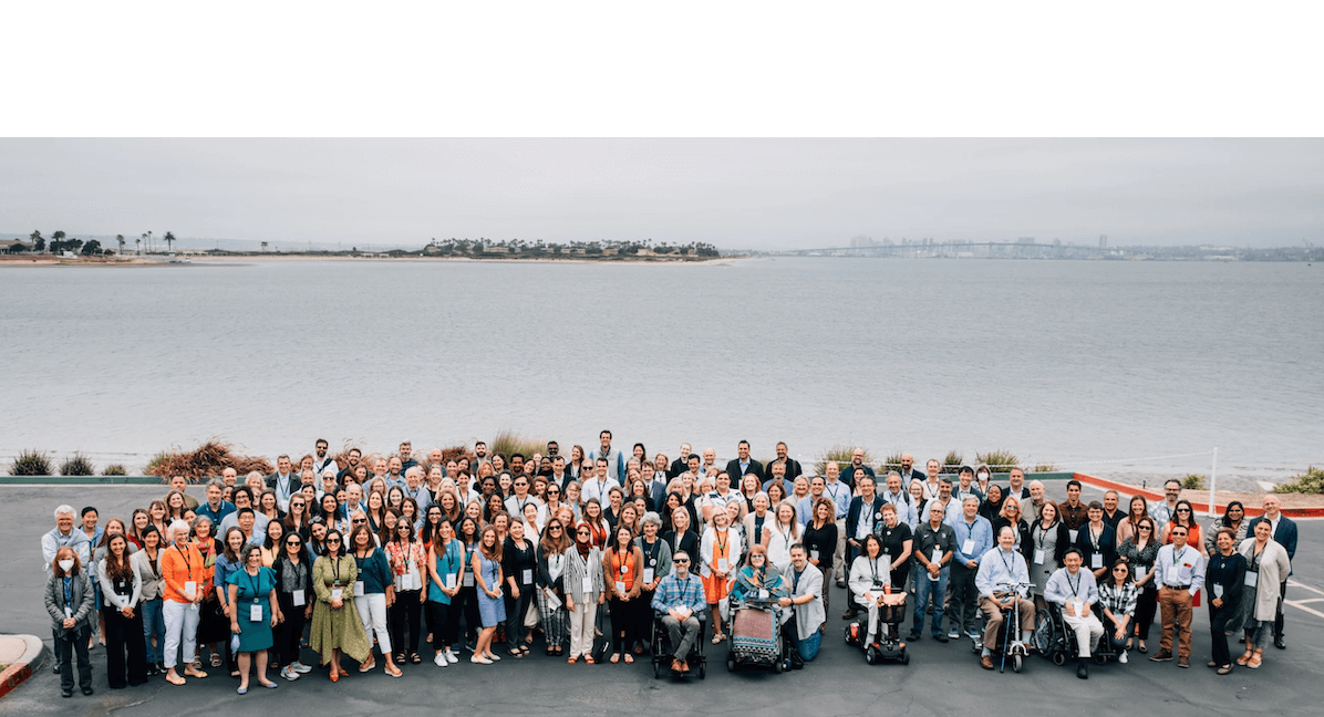 Participants stand grouped together in front of the Coronado bay. They smile at the camera.
