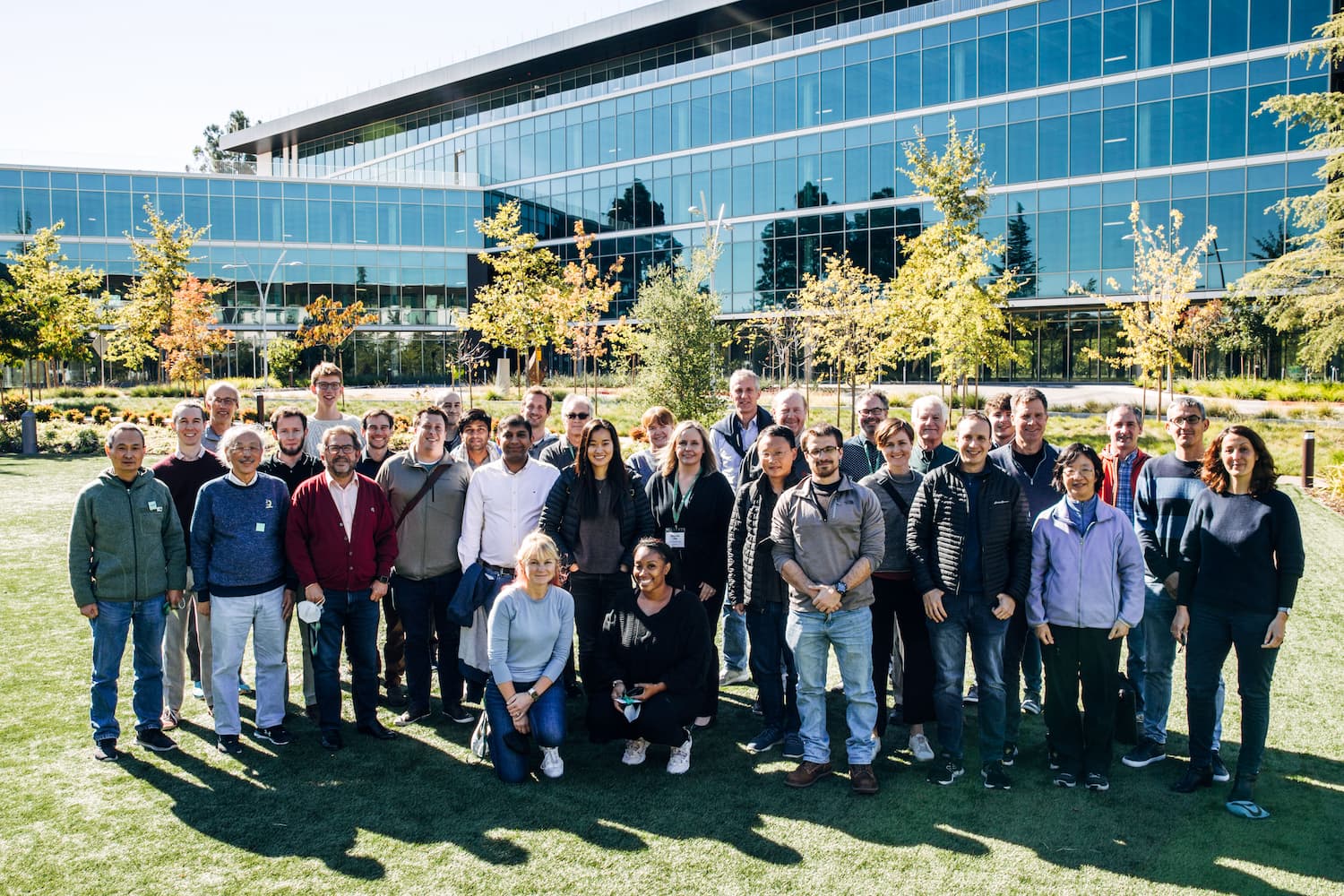 A group of participants at the CZ Imaging Institute's Computational Frontiers for CryoET Workshop stand side by side outside on a grass lawn in front of a building.