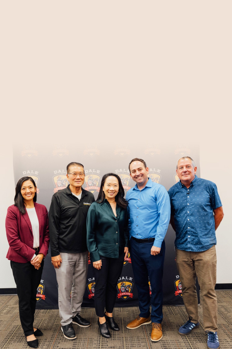 Sandra Liu Huang stands in the center, smiling alongside four school leaders, with a light pink background covering the top portion of the image.